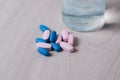 Blue and pink probiotic pills or vitamins on a wooden background. Pharmacology theme