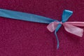 Blue and pink ribbons in the shape of a bow on a purple background. Congratulatory postcard. Copy space Royalty Free Stock Photo