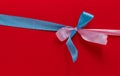 Blue and pink ribbons in the shape of a bow on a red background. Congratulatory postcard. Copy space, Royalty Free Stock Photo