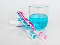 Blue and pink toothbrushes, toothpaste, mouthwash on a white glossy background. The concept of daily dental care