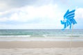 Blue pinwheel toy spinning on white sand beach, colorful wind turbine windmill on the beach with summer sea and blue sky as