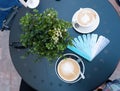 Blue planks menu with various drinks names and cups of coffee on blue table