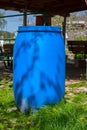Blue plastic barrel for draining rainwater from sewer pipes on green grass in summer. Large water storage barrel. Royalty Free Stock Photo