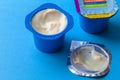 Blue plastic containers with yogurt isolated on blue background - fun creamy yogurt image and selective focus