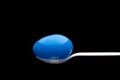 Blue plastic Easter Egg on a white spoon