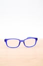 Broken blue plastic eye glasses with adhesive tape, isolated on a wooden and white background Royalty Free Stock Photo