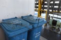 Blue plastic garbage bins for food waste firmly tight to the railings are situated behind superstructure