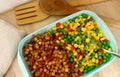 A lunchbox/plastic food container filled with vegetable mix and `pytt i panna` the swedish name for a dish with fried chopped/dice