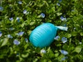 Blue Plastic nylon Easter egg among garden flowers