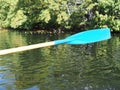 Blue plastic paddle paddles over the water after a close-up stroke. Water drops flow down Royalty Free Stock Photo