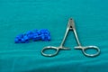 Blue plastic surgical clips and stainless applier for scalp hemostasis in brain surgery on green table in operating room