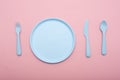 Blue plastic tableware : plate, fork, knife and spoon on pink background. Royalty Free Stock Photo