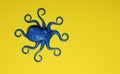 Blue plastic toy octopus on plain yellow background.