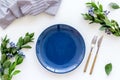 Blue plate and flowers for table setting on white background top view