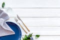 Blue plate and flowers for table setting on white wooden background top view space for text