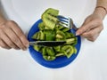 Blue plate. Girl eating a fork and knife kiwi.