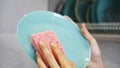 Blue plate with pink dish sponge in hand on blurred background