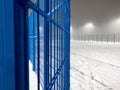 Blue playground fence in winter with snow at night