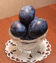 Blue plums in a glass vase.The vase stands on a napkin on the table. Royalty Free Stock Photo