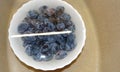 Blue plums in a white dish in jets of water.