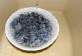 Blue plums in a white dish in jets of water.