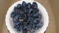 Blue plums in a white dish in jets of water.