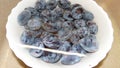 Blue plums in a white dish in jets of water.