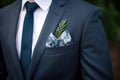 blue pocket square peeks out of a charcoal suit jacket