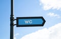 Blue pointer of public toilet sign, sign indicating of public WC against the sky