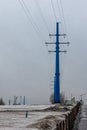 Blue poles of a high-voltage power line in a snow-covered field Royalty Free Stock Photo