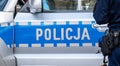 Blue Polish police vehicle and a policeman, policja, police car side detail, closeup. Polish emergency services simple concept,