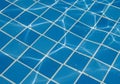 Blue pool tiles underwater create a grid pattern with white grout lines. Reflected sunlight Royalty Free Stock Photo