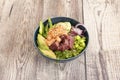 Blue porcelain bowl filled with red tuna, marinated salmon, red onion, green wild asparagus, ripe avocados, soy sauce, edamame