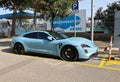 Blue Porsche Taycan Turbo on charging at the roadside.