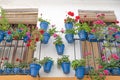 Blue pots hanging on Andalusian balcony of pink and red geraniums