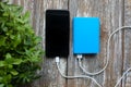 Blue power bank with white usb and black smart phone on old vintage wooden background. Modern, information technology photo near Royalty Free Stock Photo