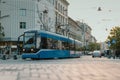 Blue public tram in the city of Krakow, Poland on early summer evening, riding through the streets of busy city. Modern tram in