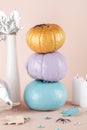 Blue purple and gold pumpkins with candles and vase on beige background Royalty Free Stock Photo