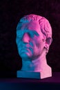 Blue purple gypsum copy of ancient statue of Guy Julius Caesar Octavian Augustus head for artists on dark textured Royalty Free Stock Photo