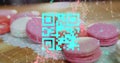Blue QR code with a red floating web of connections over pink macaronies lying on a table Royalty Free Stock Photo