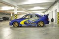The blue Subaru Impreza stands in which garage and wears yellow stickers on the foil