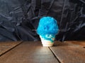 Blue raspberry Hawaiian Shave ice, Shaved ice or snow cone in a clear plastic cup with ice cream with a black background. Royalty Free Stock Photo