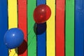 Blue and red balloon on a colourful fence