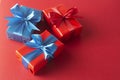 Blue and red gift boxes with red ribbon and bow isolated on red background, top view. Christms, party concept