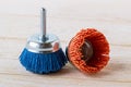 Blue and red nylon abrasive brushes for drill on a white wooden surface. Tools for cleaning, polishing and grinding of wood and