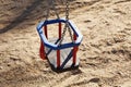 A blue and red swing in the sandbox