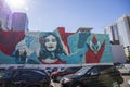 A blue and red wall mural with a picture of a woman with a flower in her hair surrounded by skyscrapers and office buildings