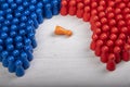 Blue and red wooden figurines surrounding a fallen orange figurine, symbol for failed leader