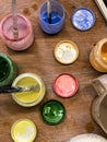 Blue, red, yellow, green pottery glaze liquid in jars with brushes on table top view in pottery studio
