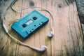 Blue retro cassette tape and white earphone on wooden table Royalty Free Stock Photo